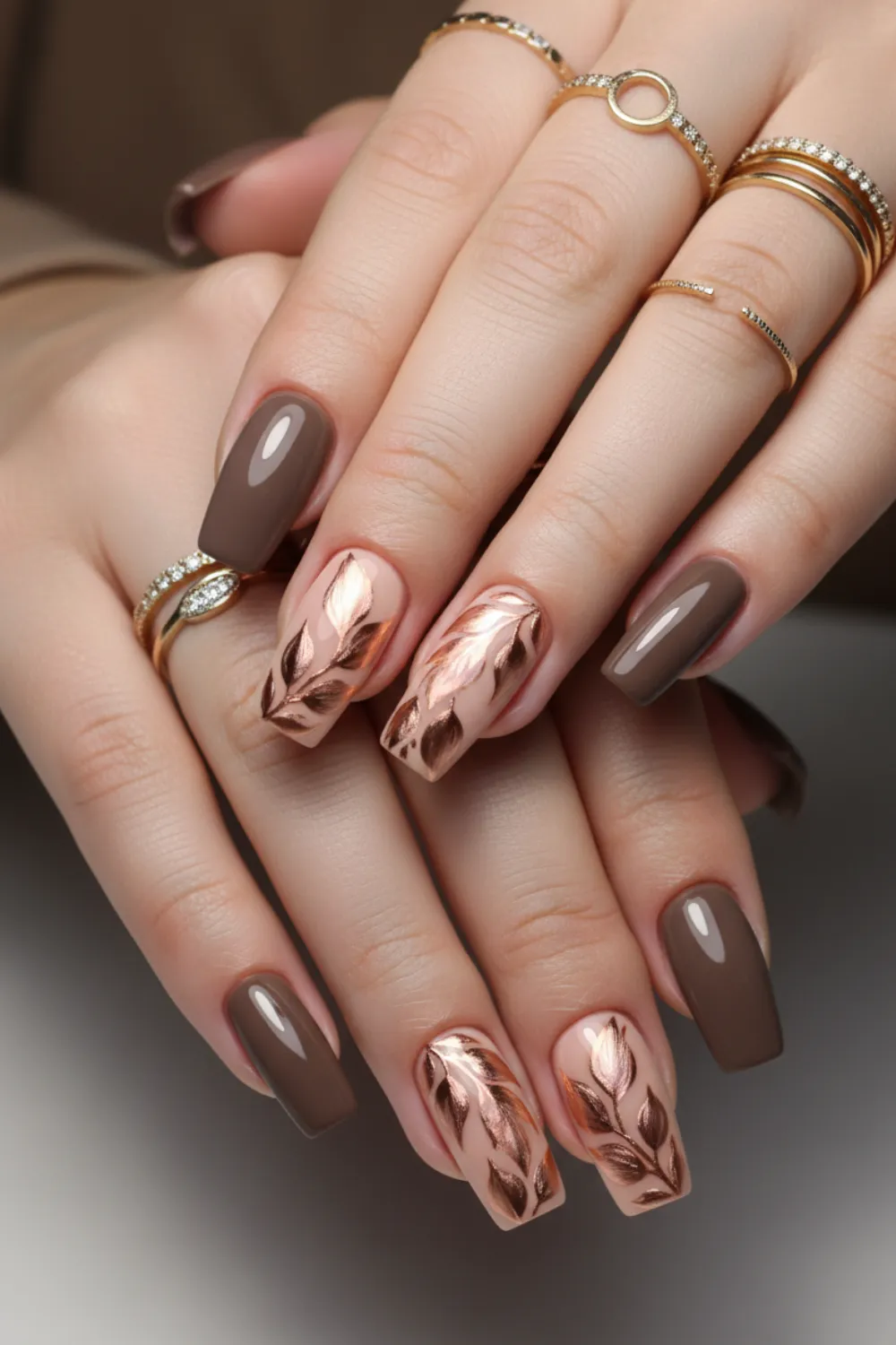 Mocha brown coffin nails with rose gold leaf art on nude accent nails