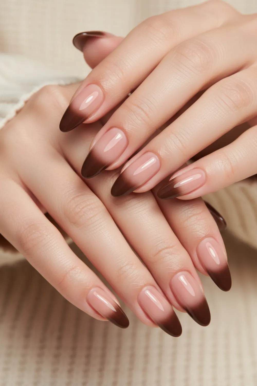 Almond nails with a pale nude base and a short chocolate brown ombre at the tips
