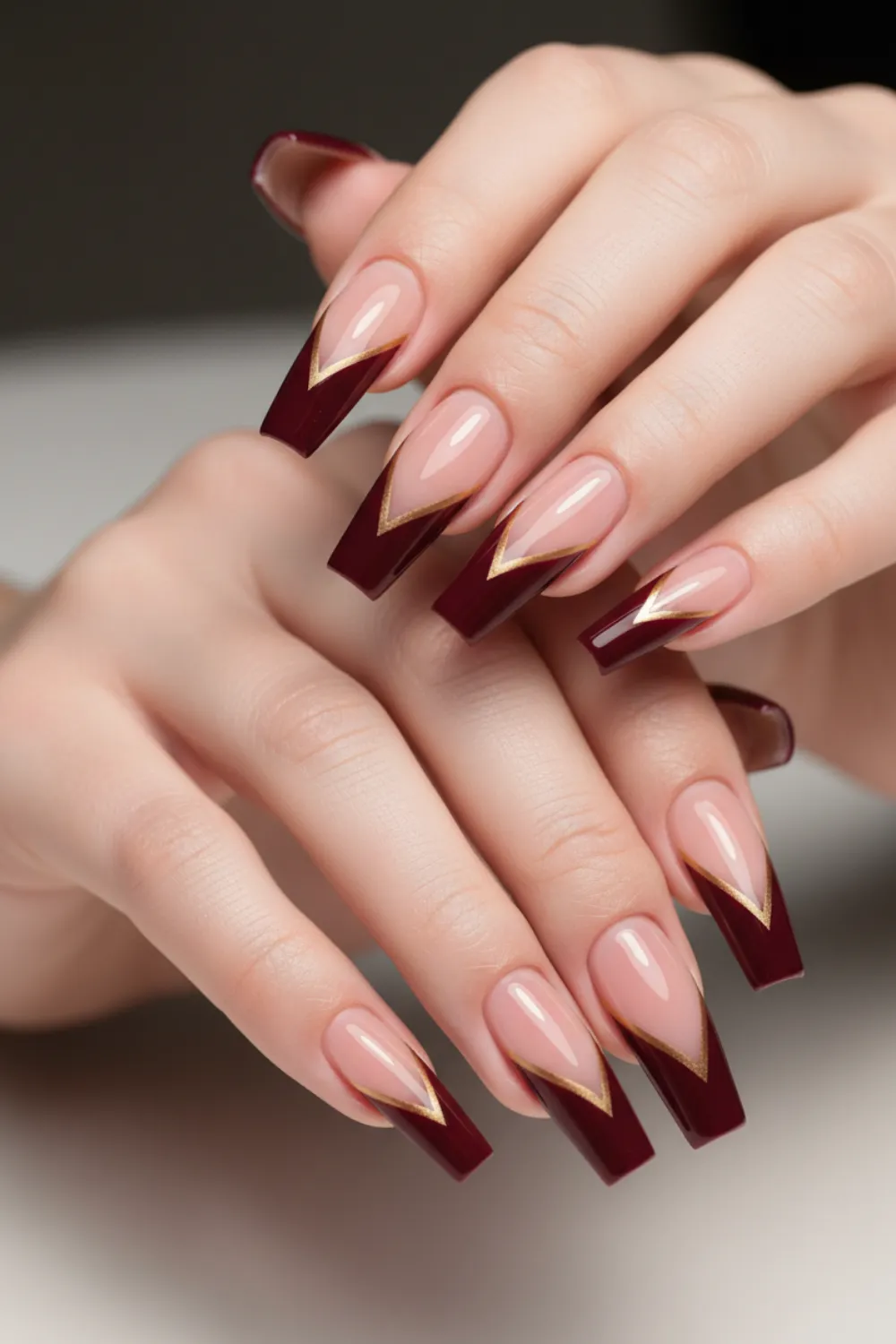 Almond nails with deep burgundy V-shaped French tips