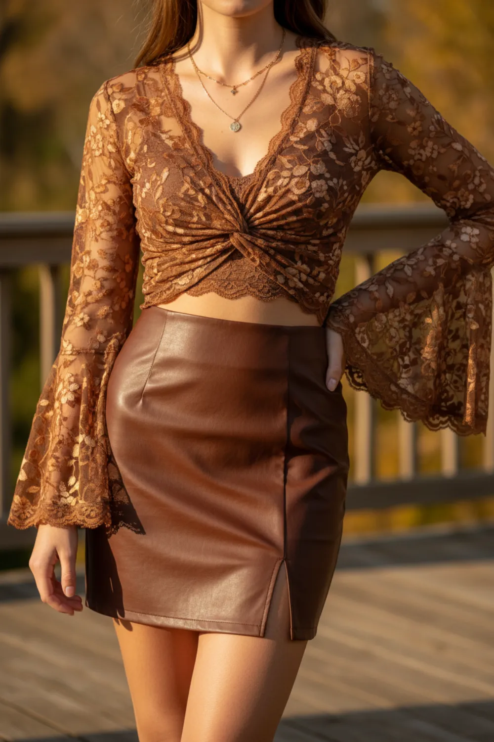 Brown lace bell-sleeve wrap top with a brown leather mini skirt and layered gold necklaces