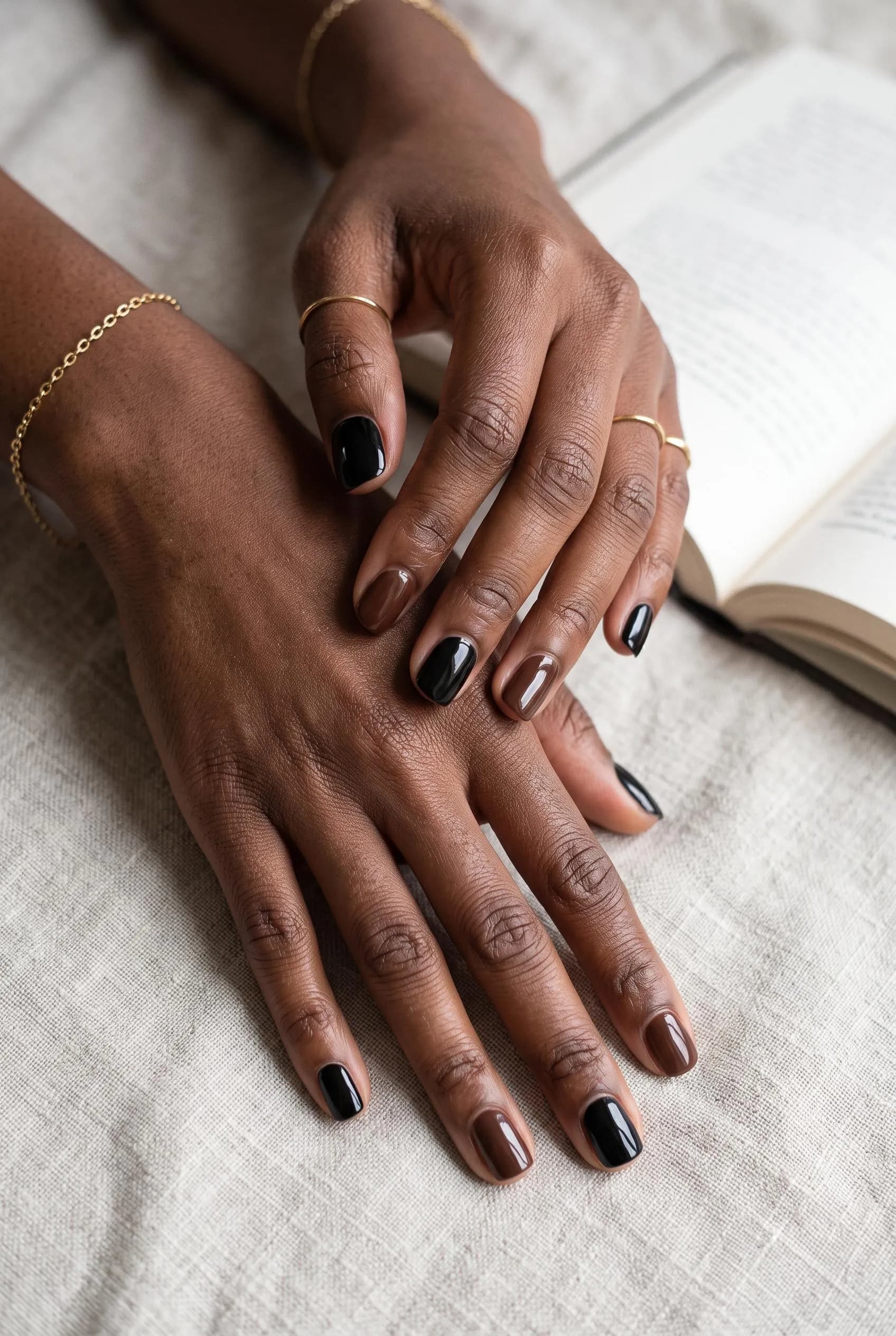 Short nails alternating jet black and chocolate brown on deep brown skin