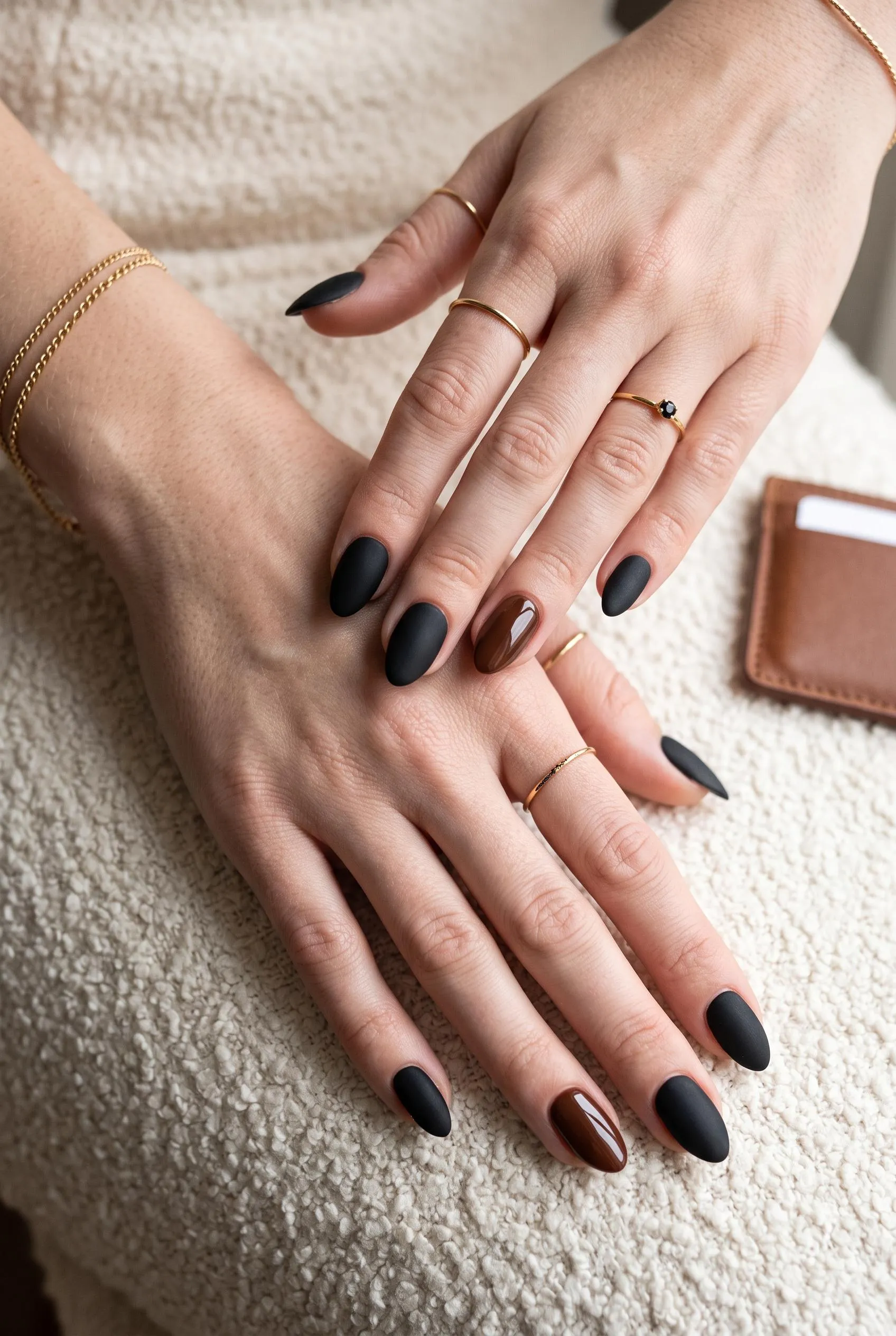 Matte black almond nails with glossy chocolate brown ring-finger accents