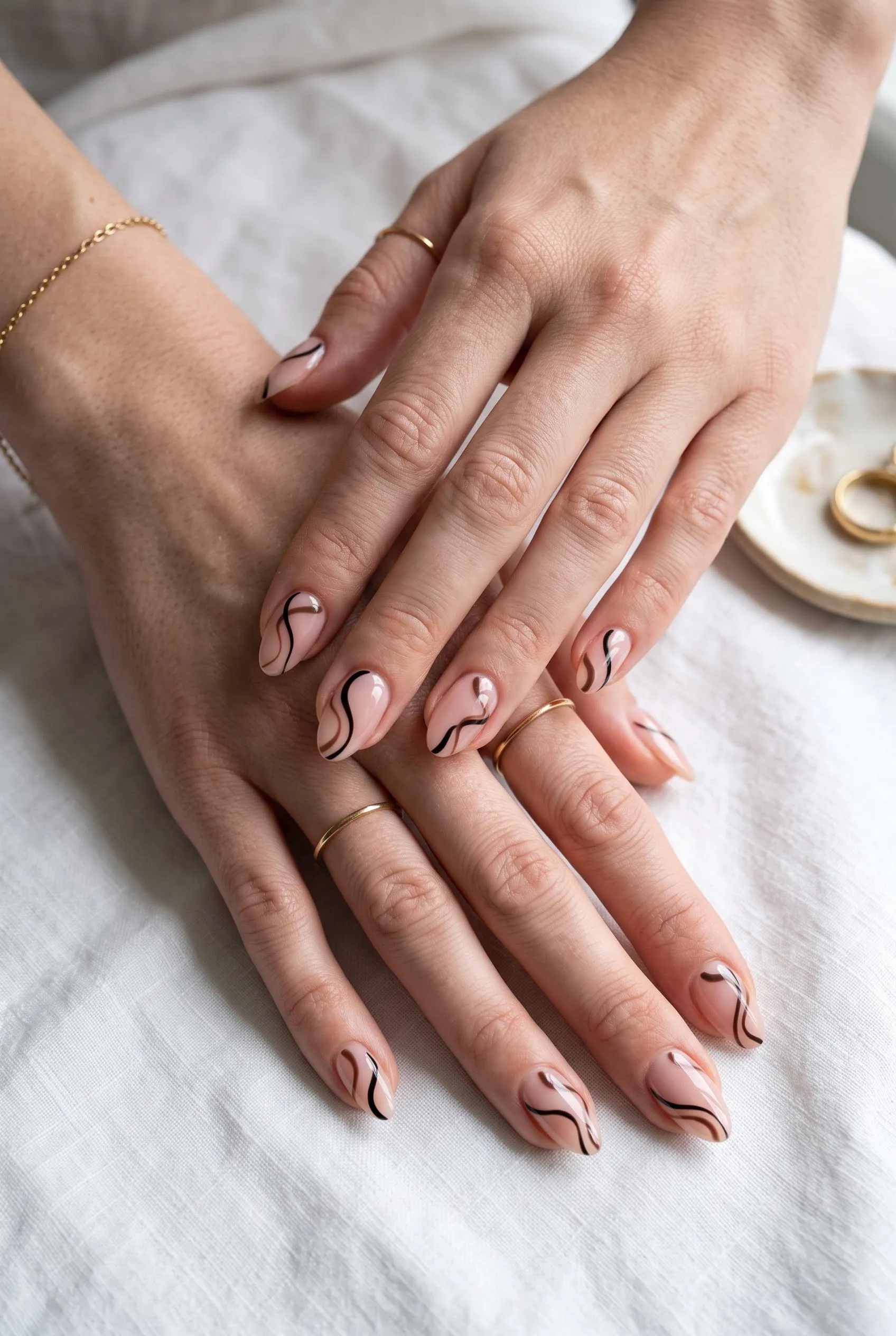 Sheer nude nails with thin black and brown abstract swirls