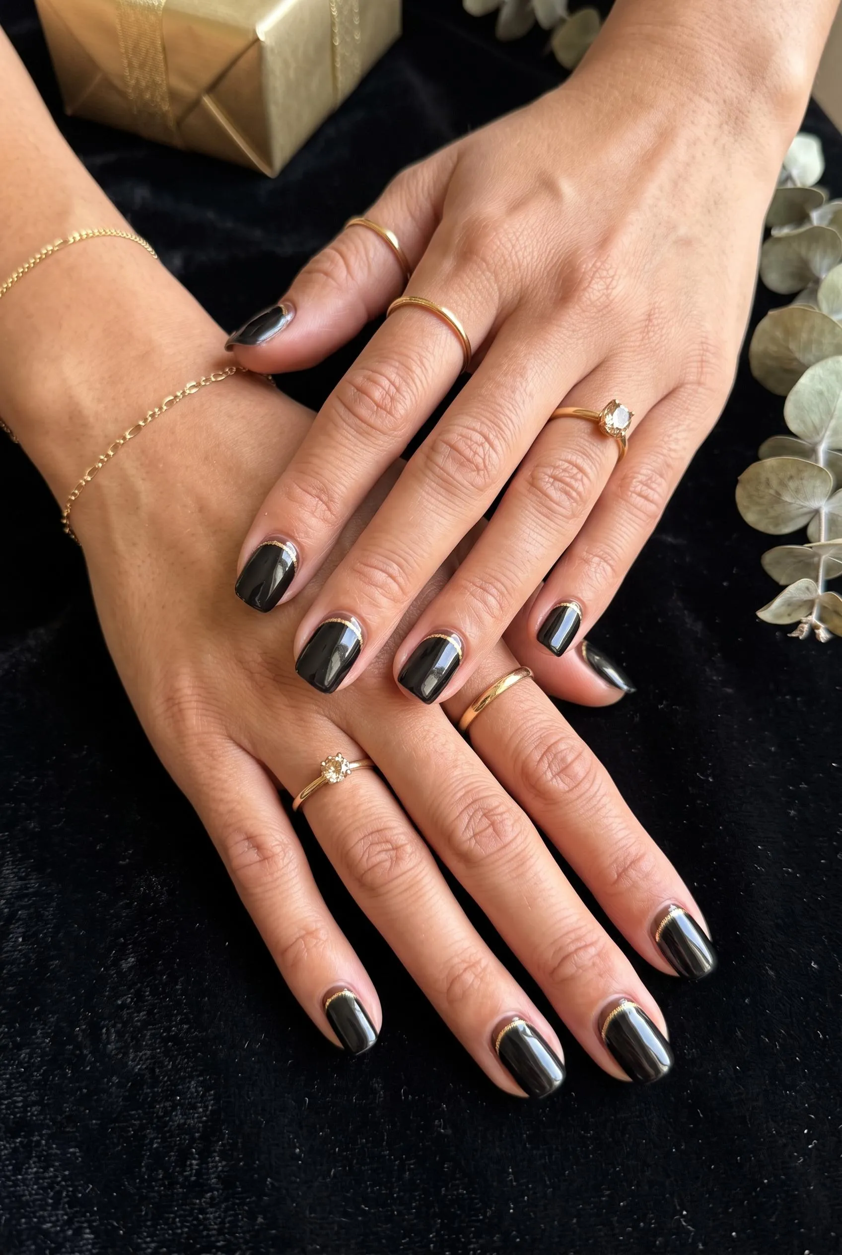 Glossy black nails with a thin brown and gold cuticle line