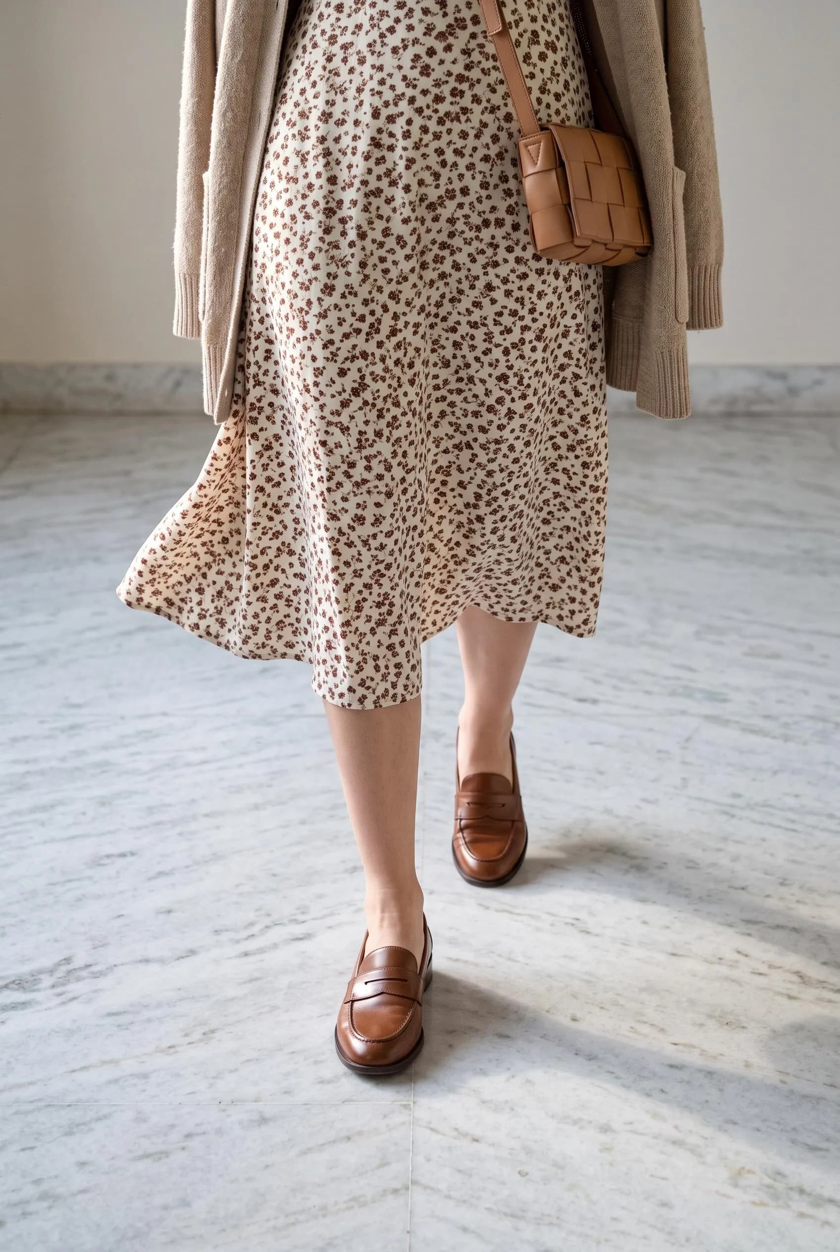 Brown penny loafers with a cream spotted-print midi dress and a beige cardigan