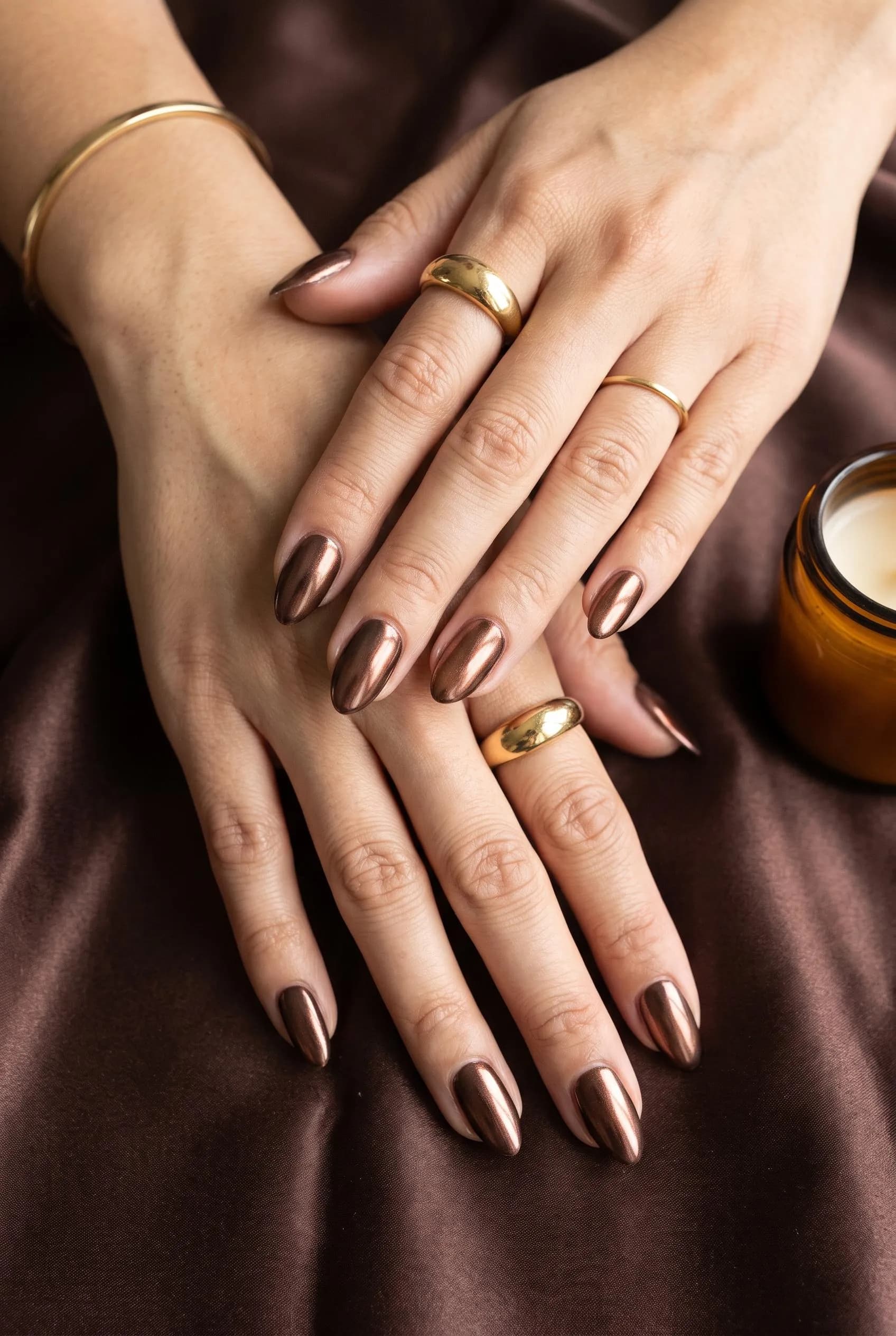 Chocolate almond nails with a bronze chrome finish on brown satin
