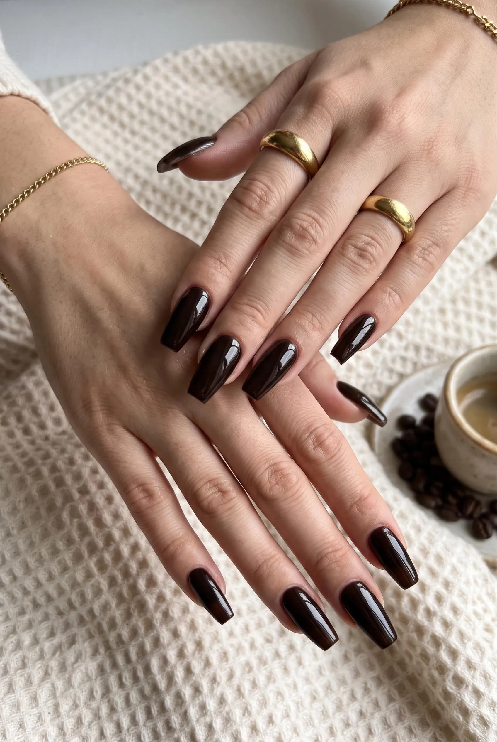 Long glossy espresso brown coffin nails beside an espresso cup