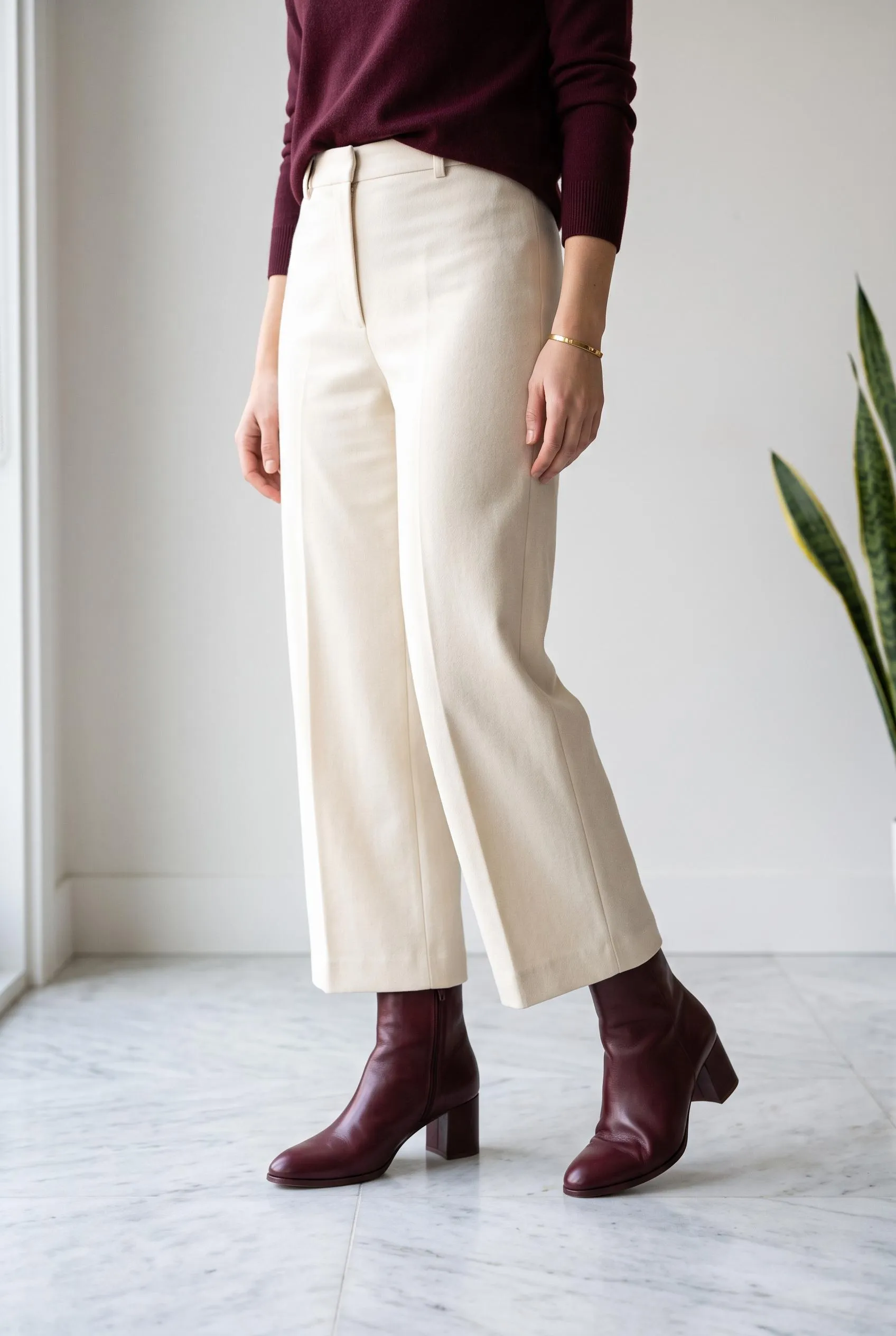 Burgundy ankle boots with a matching burgundy sweater and cream wide-leg trousers