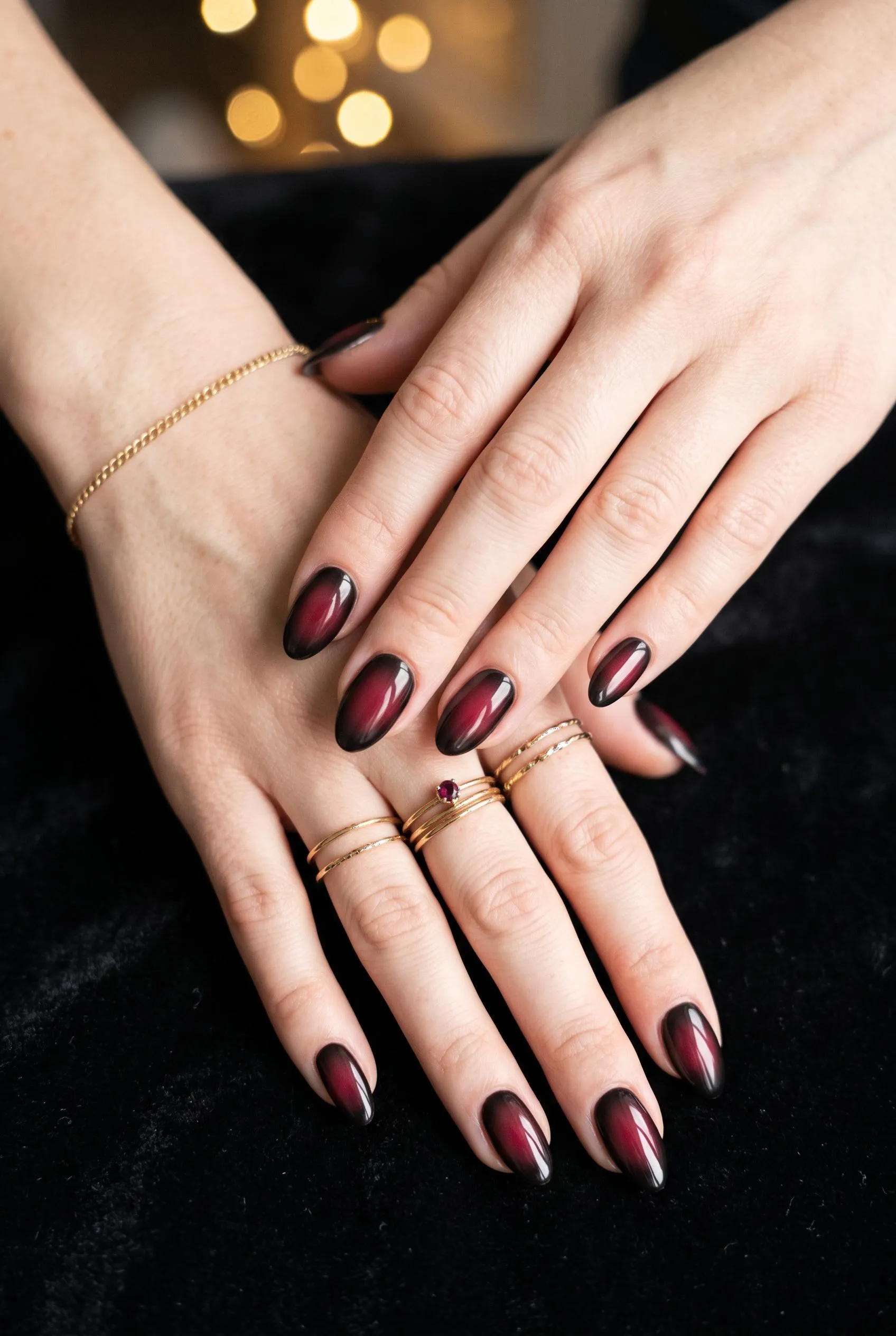 Burgundy and black aura almond nails on black velvet