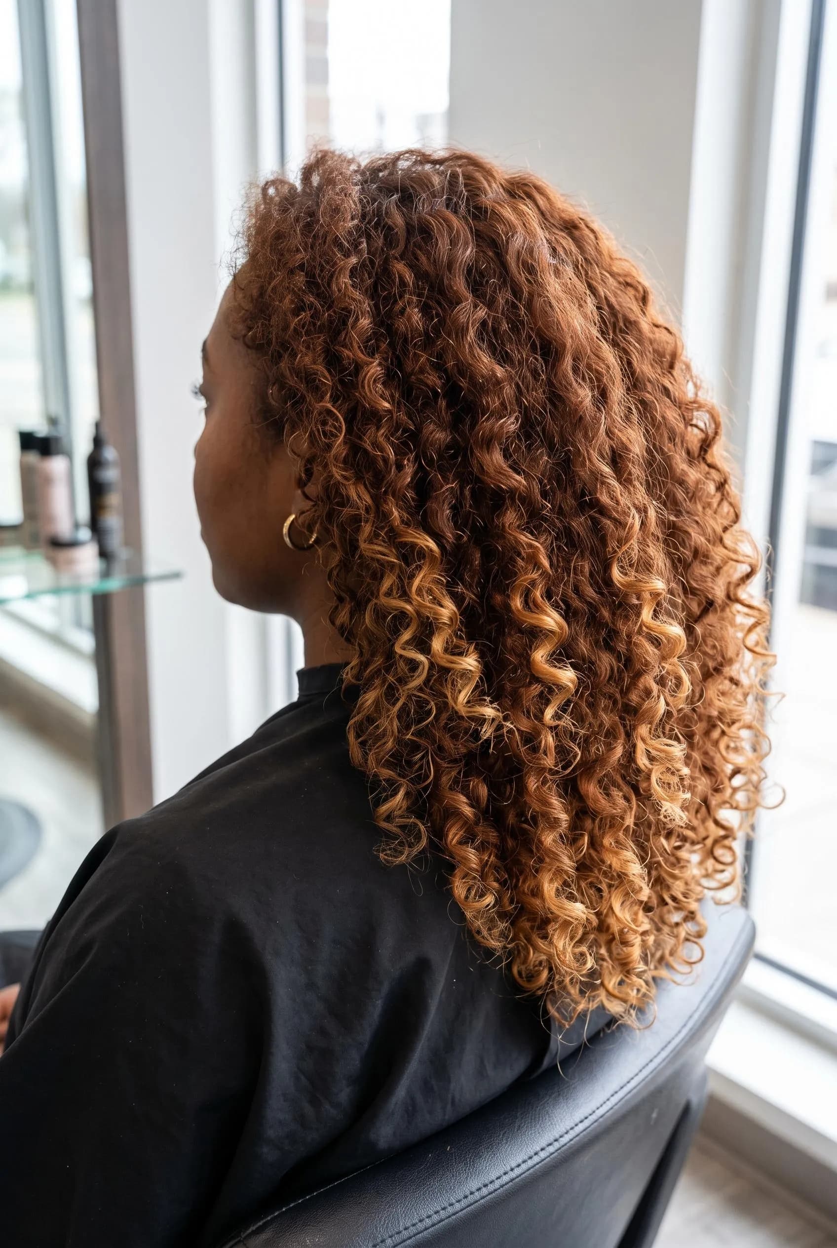 Defined copper brown curls with warm blonde painted on the ends