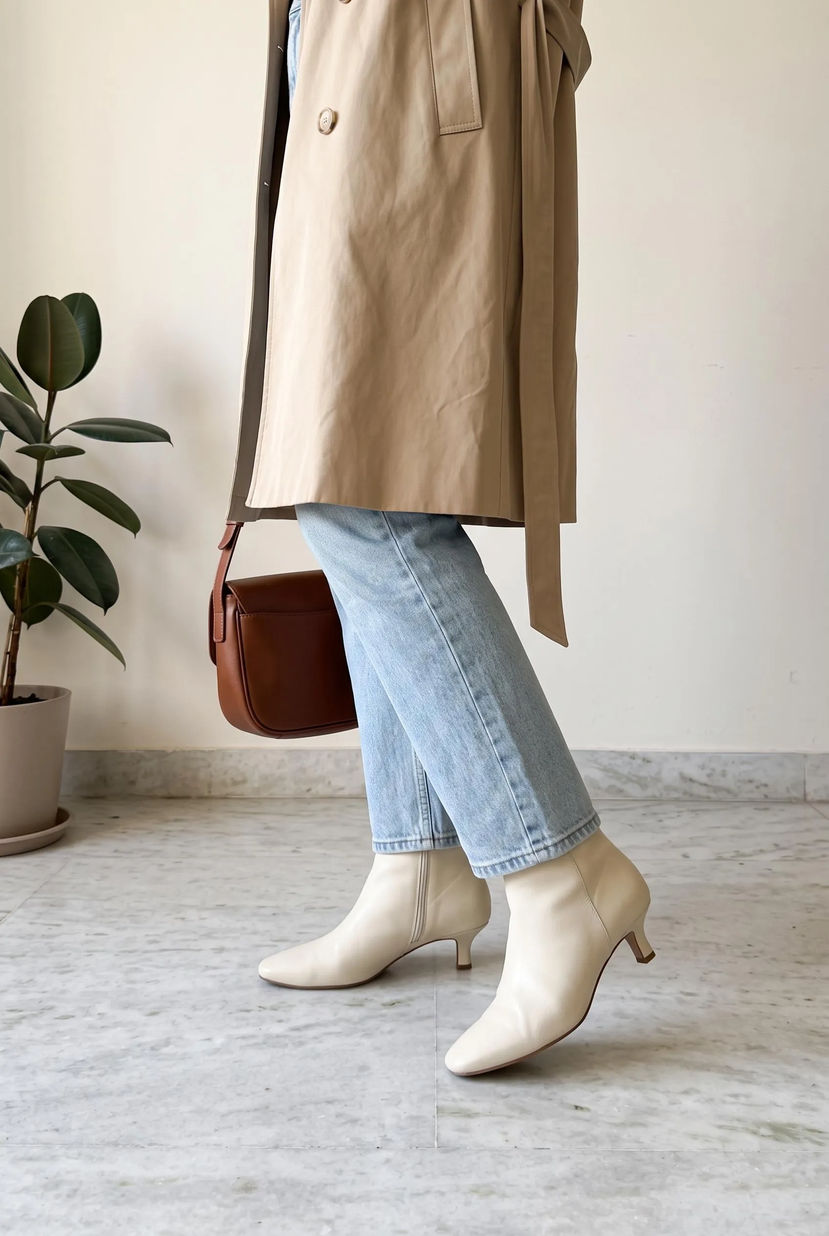 Cream ankle boots with light-wash jeans and a beige trench coat