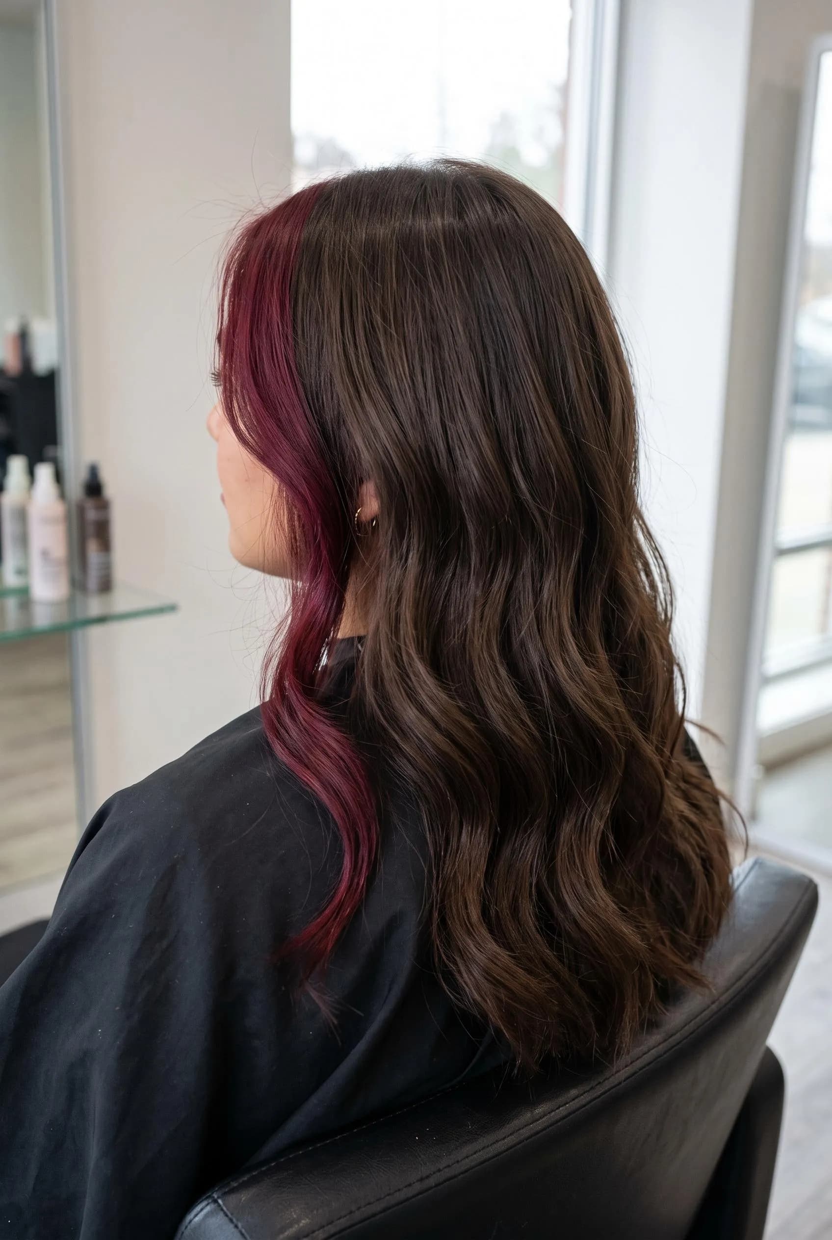 Dark brown waves with a bold burgundy money piece framing the face