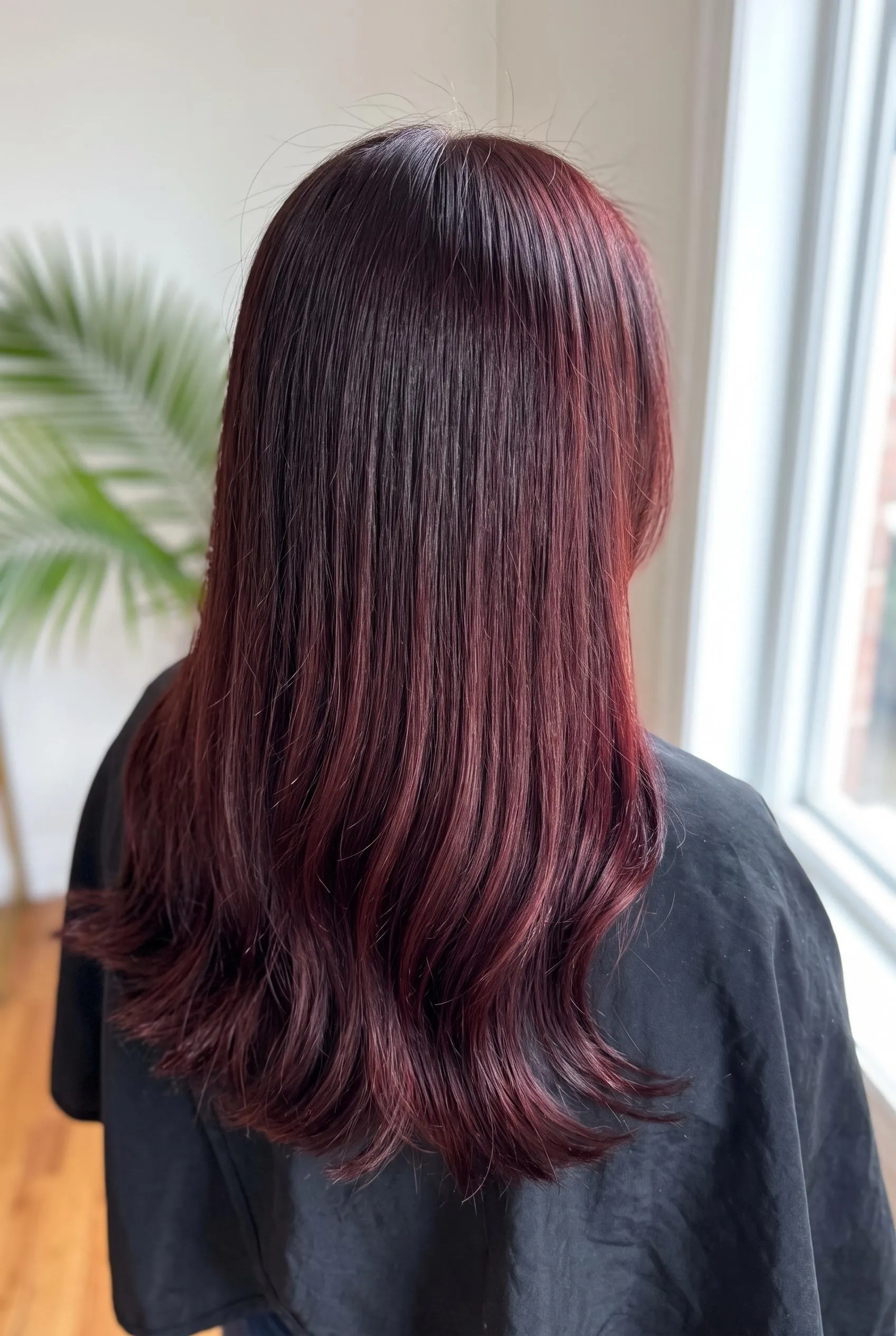 Long dark brown hair with a red-violet cherry cola tint in a salon