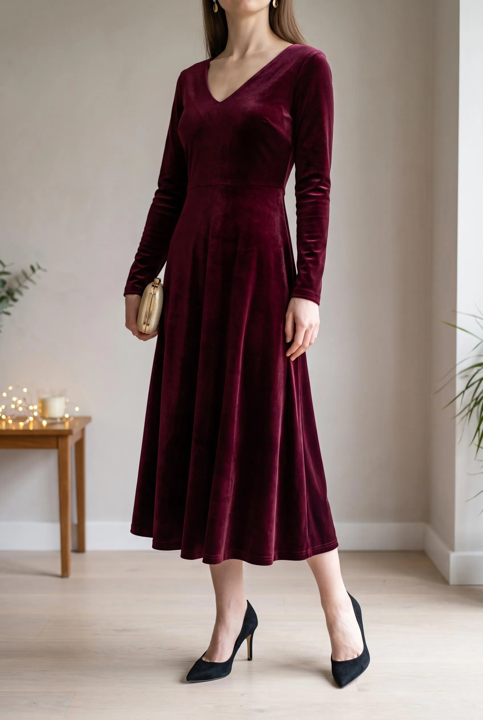 Burgundy velvet long-sleeve midi dress with black pointed heels and a gold clutch