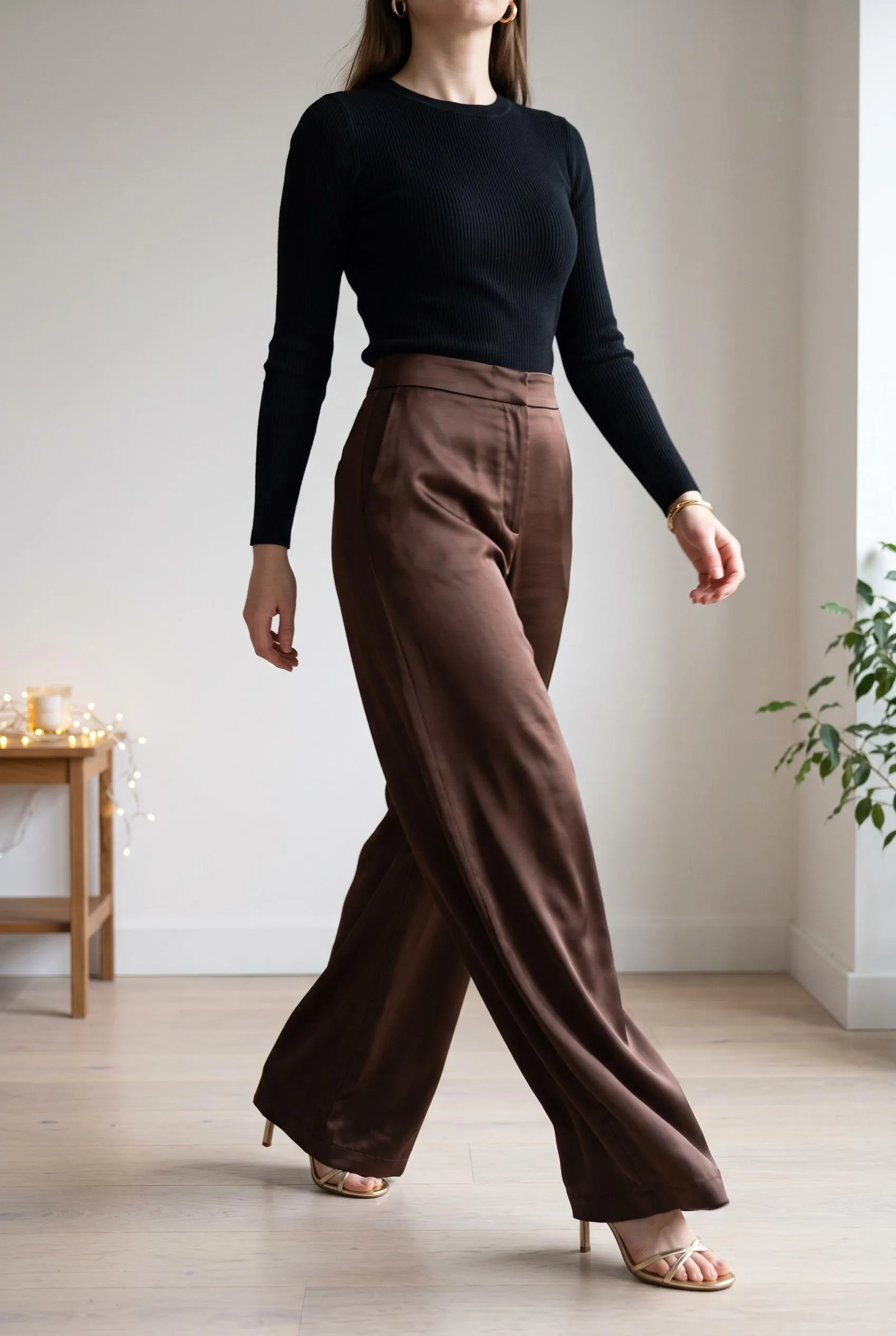 Chocolate satin wide-leg trousers with a black ribbed knit and gold strappy sandals