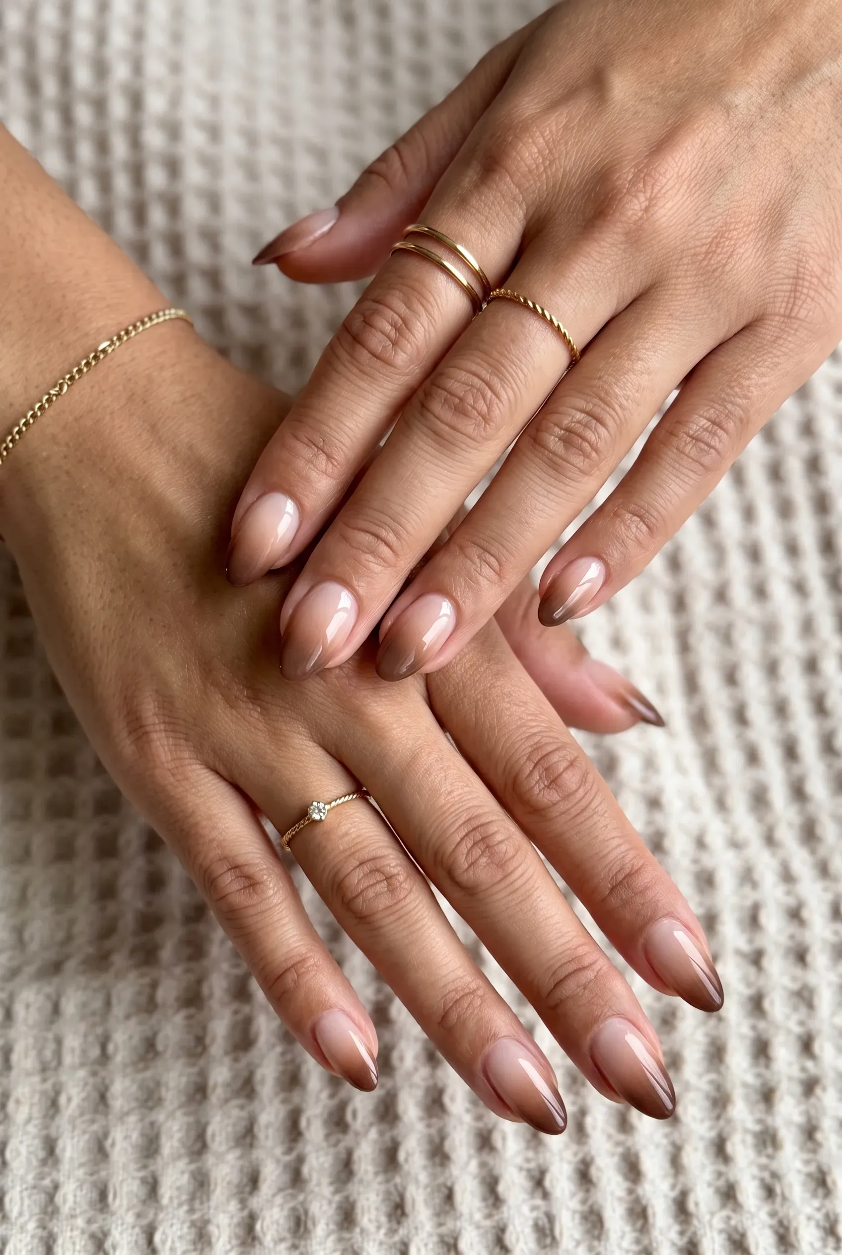 Almond nails fading from sheer nude at the cuticle to mocha brown at the tips