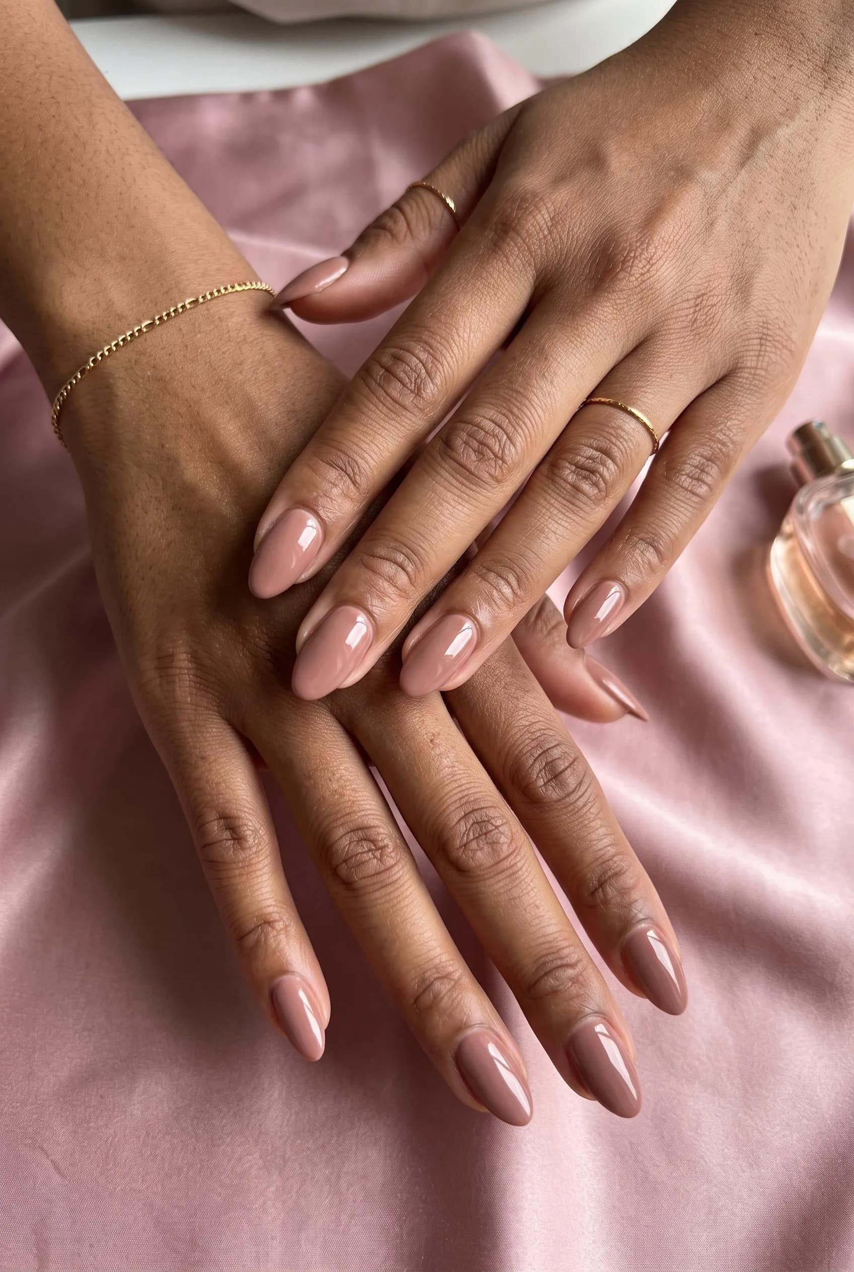 Rosy taupe almond nails on medium-deep brown skin over dusty pink silk