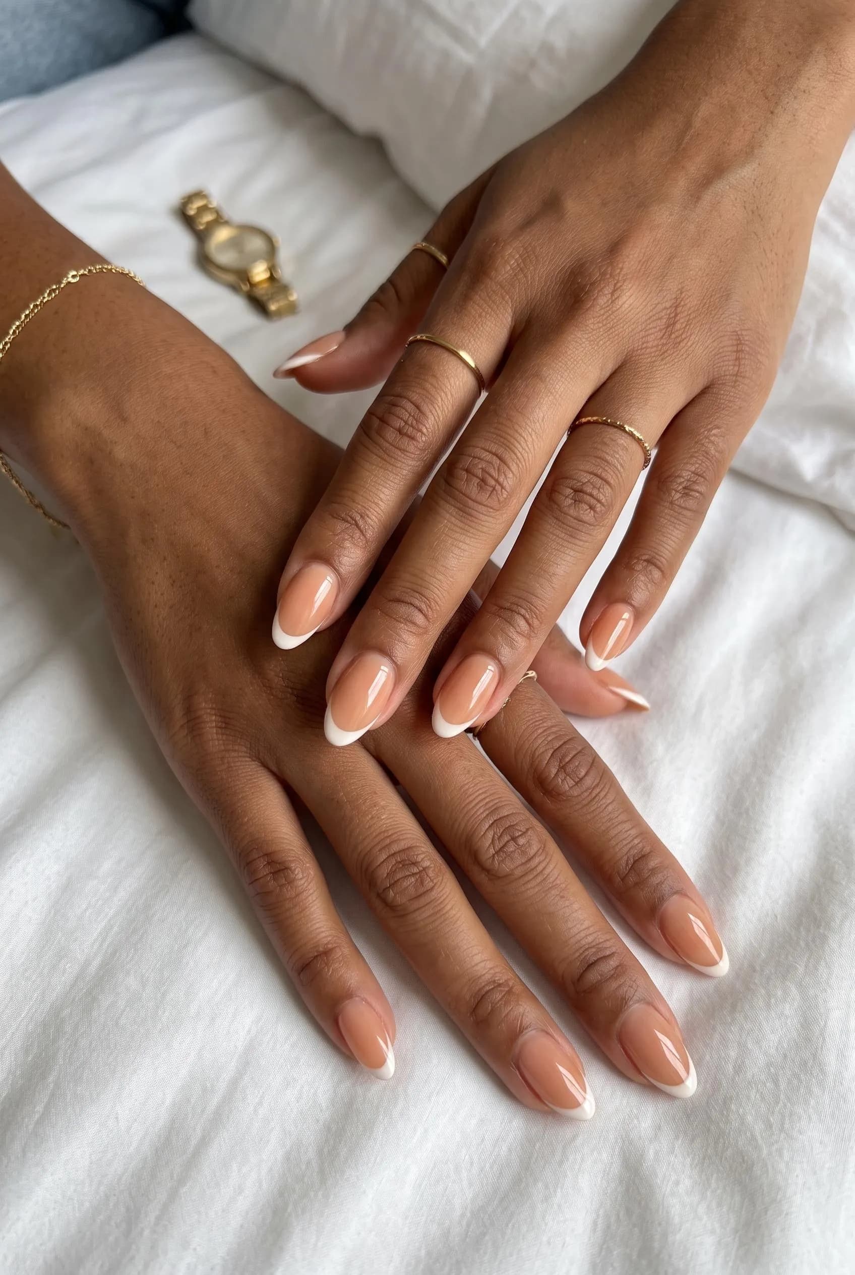 Sheer nude almond nails with thin soft-white French tips on brown skin