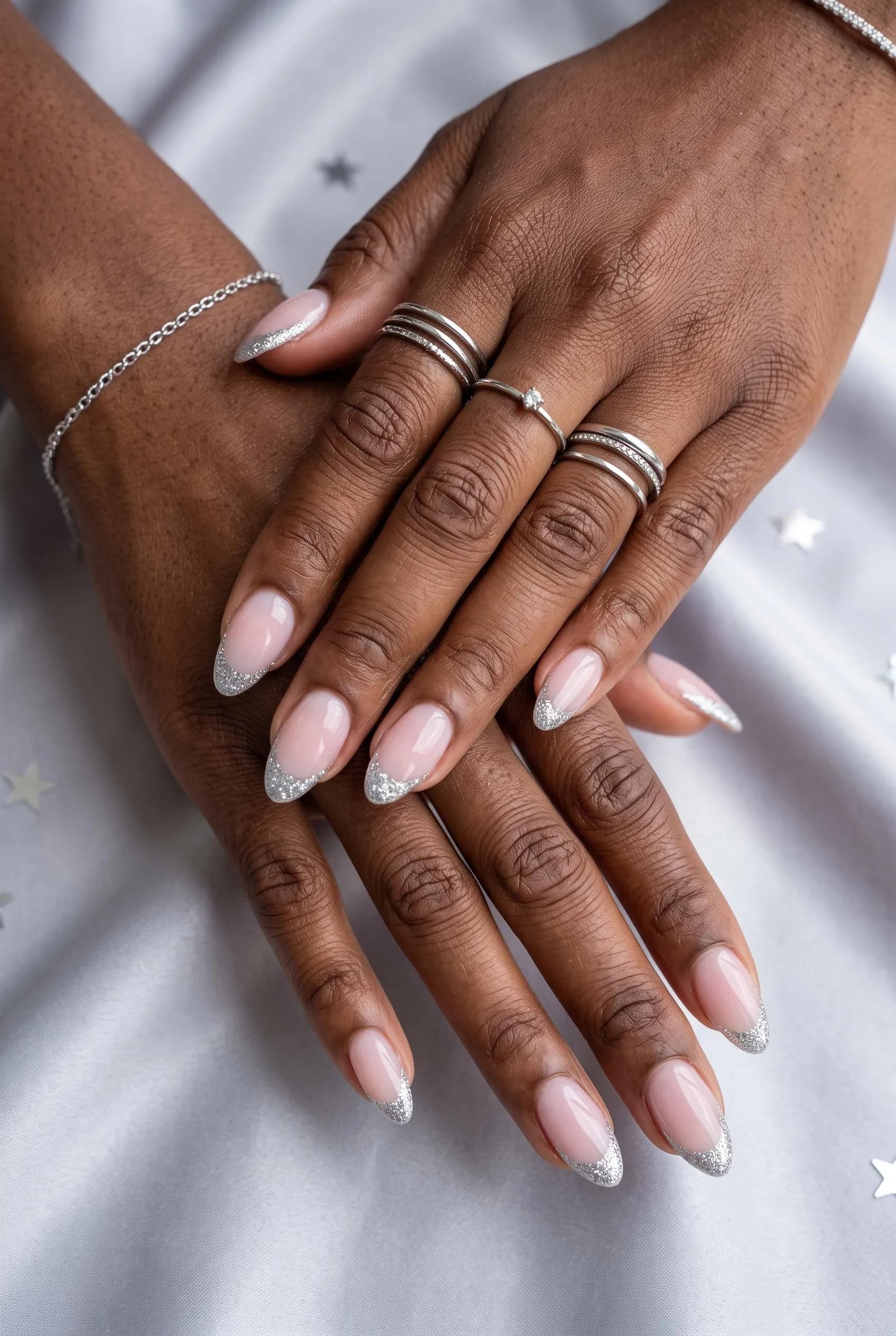 Milky pink almond nails with silver glitter French tips on deep brown skin