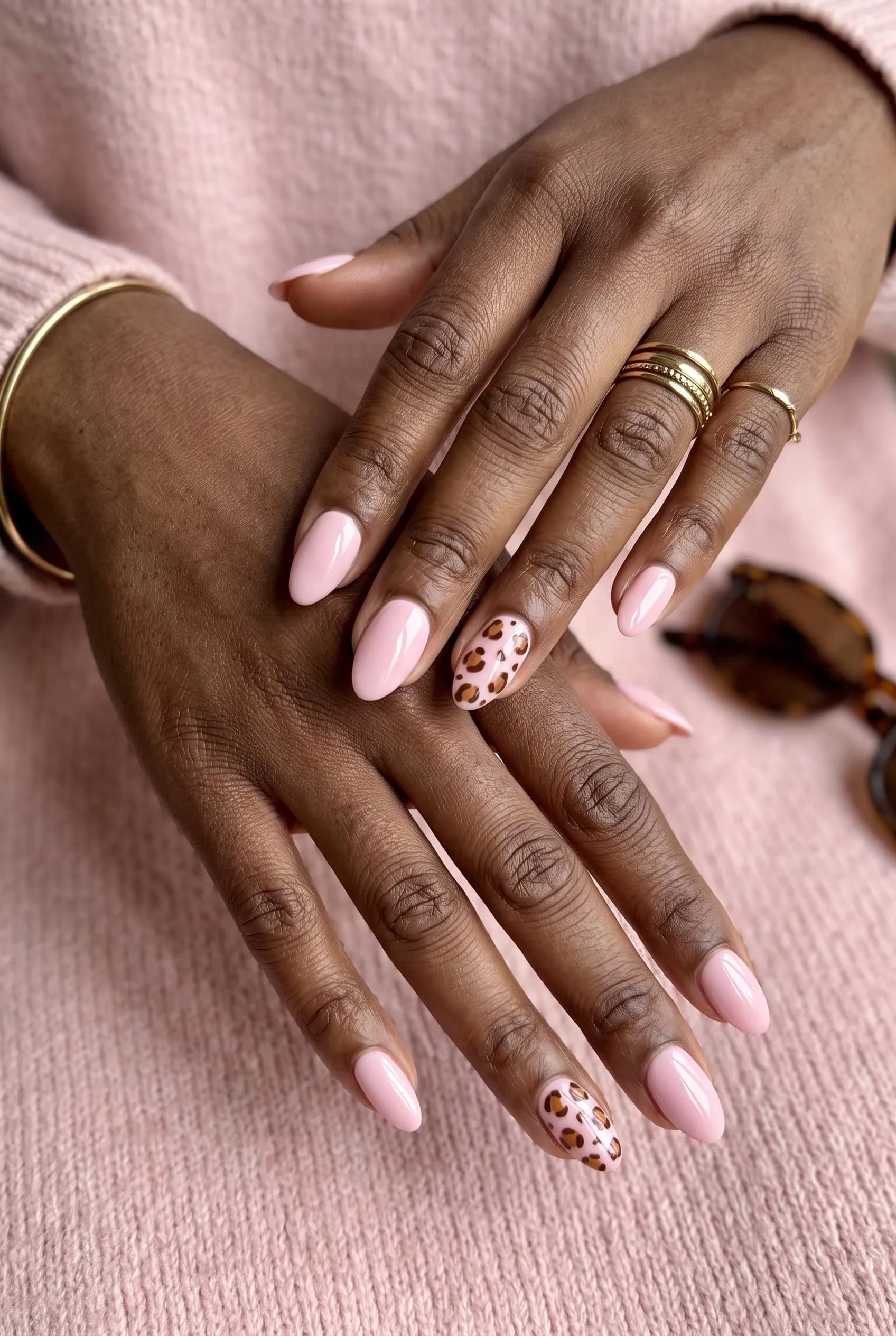 Baby pink almond nails with brown leopard print accents on deep brown skin