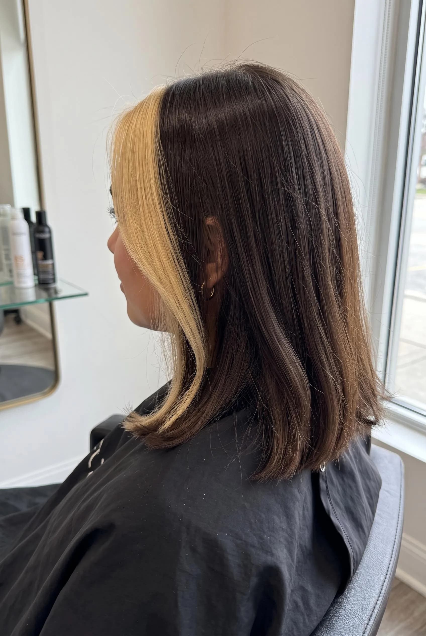 Dark brown lob with a bright blonde money piece framing the face