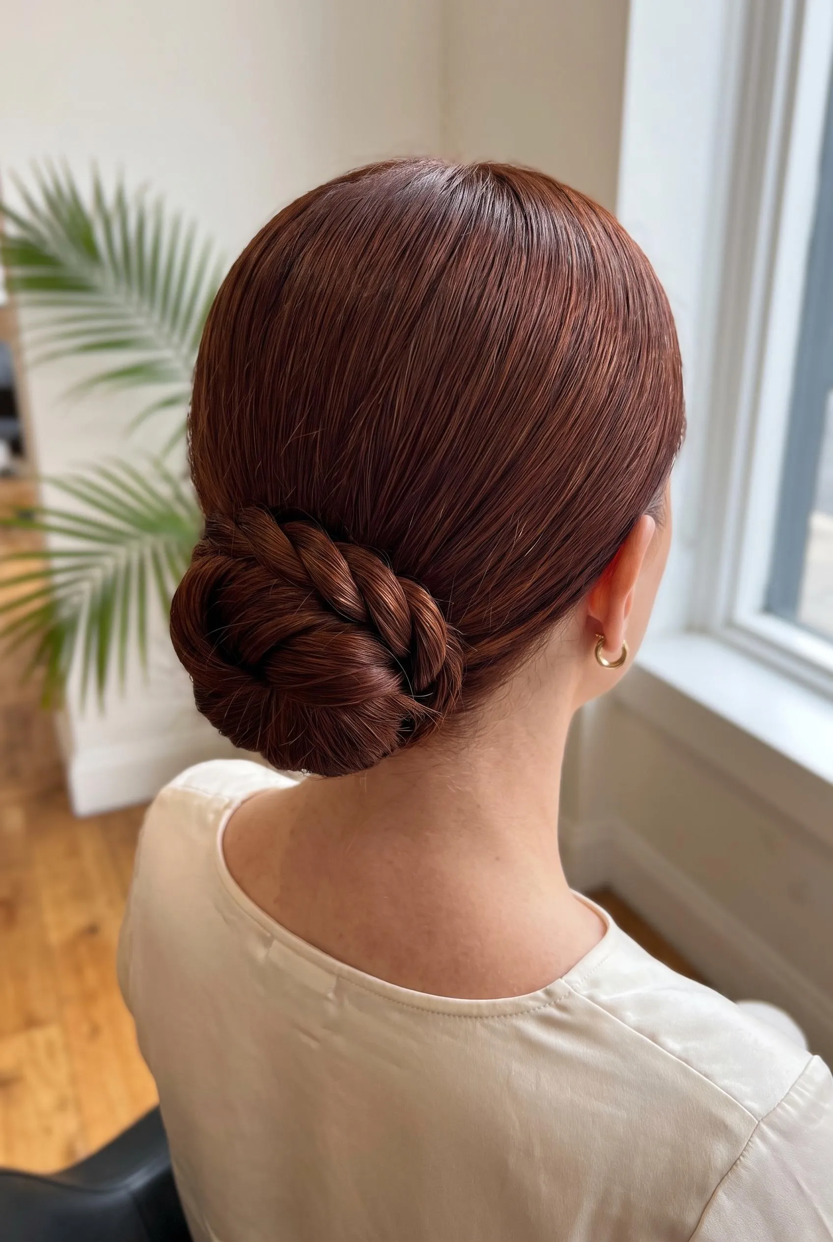 Two sleek twisted sections wrapped into a low bun on auburn hair